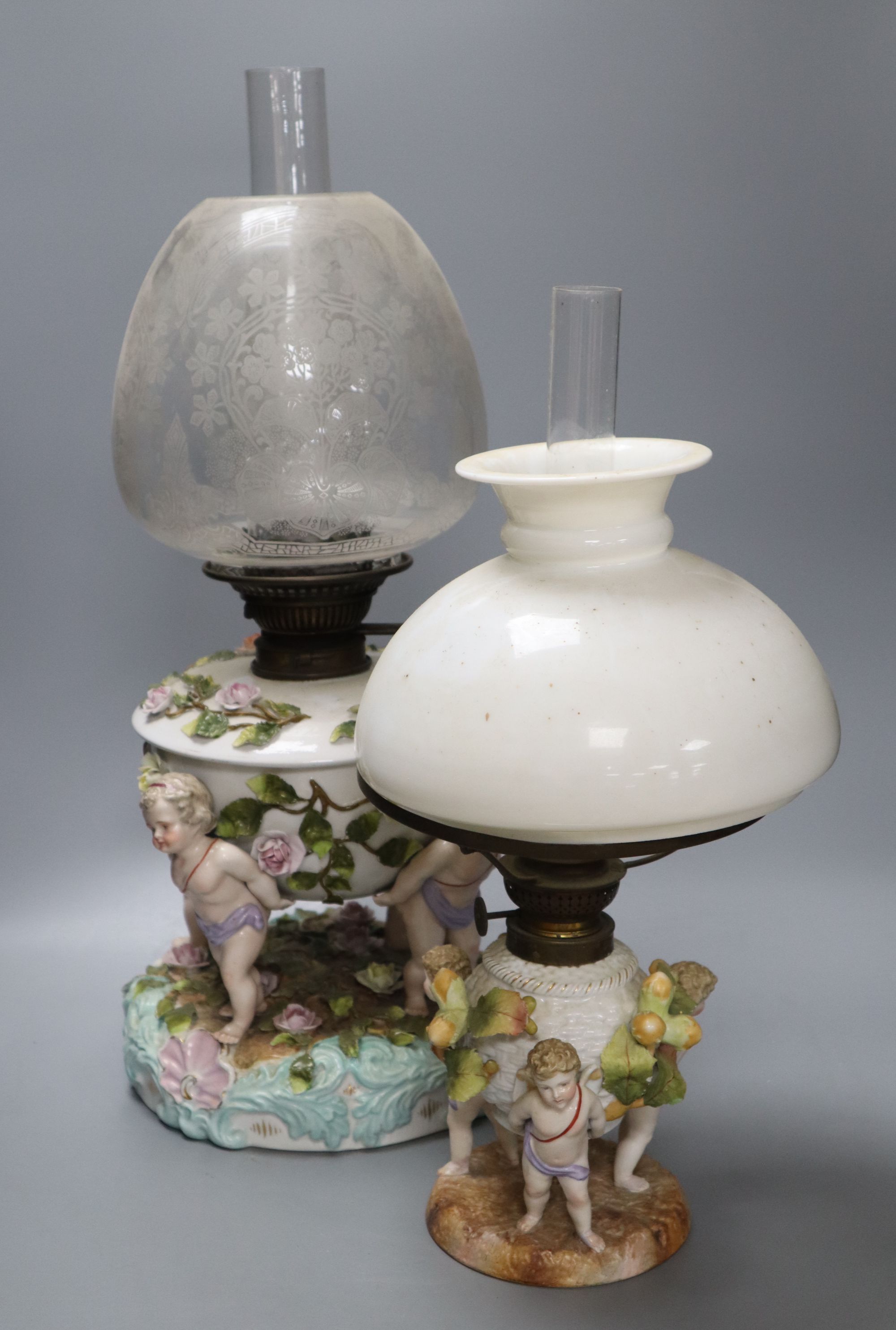 A Sitzendorf porcelain oil lamp and another similar smaller oil lamp, tallest 54cm including including shade and chimney